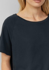 Marineblauw T-shirt met korte mouwen, gemaakt van zachte katoen, met een brede halslijn en een subtiele geribbelde textuur op de mouwen en de zoom.