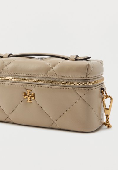 Bolsa de couro bege acolchoada com um fecho dourado e acabamentos em tom dourado, apresentando um detalhe com o logótipo e uma alça curta, textura suave e forma retangular.