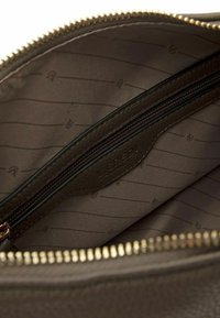 Innenansicht einer braunen Ledertasche mit einer Reißverschlusstasche, ausgestattet mit einem gemusterten Futter und einem goldenen Reißverschluss. 