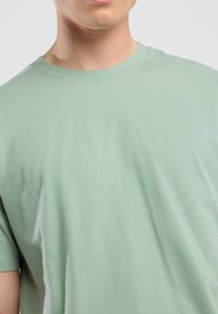 Light green short-sleeve t-shirt made of soft cotton fabric. Features a classic crew neckline and smooth texture with minimal design details.
