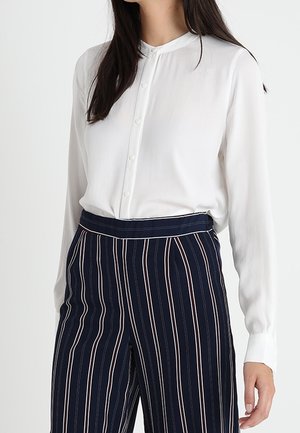 Witte blouse met lange mouwen, een bandkraag en een knoopsluiting aan de voorkant, gecombineerd met marineblauwe en witte gestreepte hooggetailleerde broek met een getailleerde pasvorm.