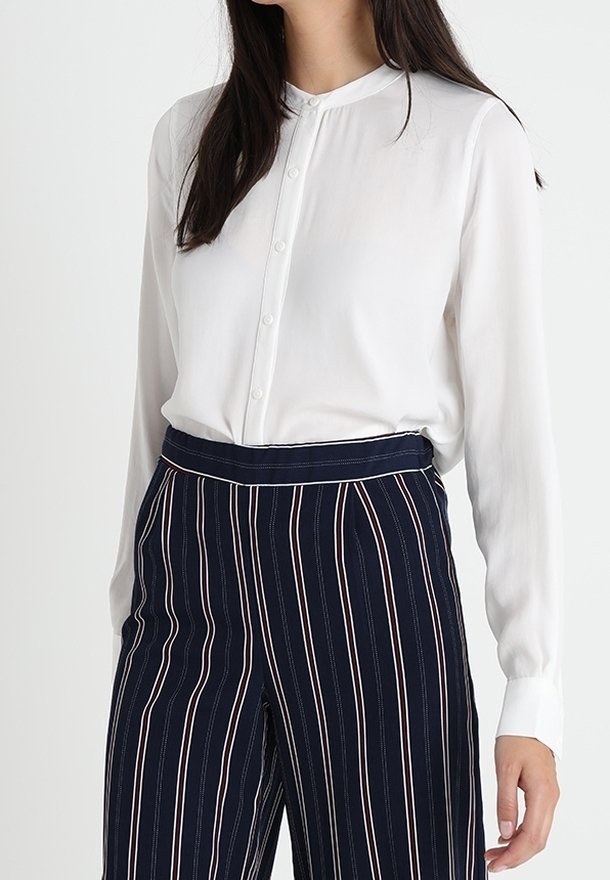 Witte blouse met lange mouwen, een bandkraag en een knoopsluiting aan de voorkant, gecombineerd met marineblauwe en witte gestreepte hooggetailleerde broek met een getailleerde pasvorm.