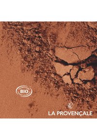 Matériau cosmétique brun en poudre avec des textures variées et une surface craquelée. Logo de la marque "LA PROVENÇALE" et étiquette "BIO" visibles.