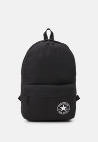 Schwarzer Rucksack aus robustem Material, mit runder Form, Fronttasche und einem bedruckten Logopatch. Zwei verstellbare Träger oben.
