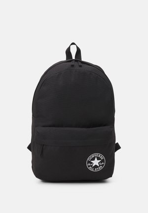 Zaino nero realizzato in tessuto resistente, con una forma arrotondata, tasca frontale e una toppa con logo stampato. Due spallacci regolabili sulla parte superiore.