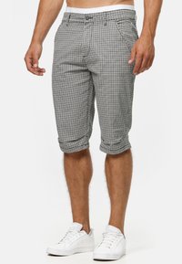 Herren-Shorts in schwarzem und weißem Karomuster, mit Knopfverschluss, Fronttaschen und umgeschlagenen Säumen, aus leichtem Material gefertigt.