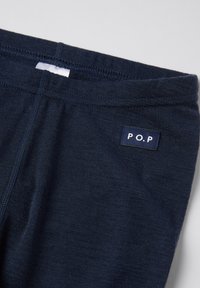 Close-up van marineblauwe stof met een genaaid label met de tekst "P.O.P" op het bovenste taillegebied.