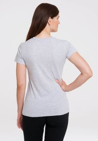 Grå kortærmet t-shirt med rund hals og tætsiddende silhuet. Stoffet har en blød tekstur og en subtil heather-mønster. Sorte bukser.