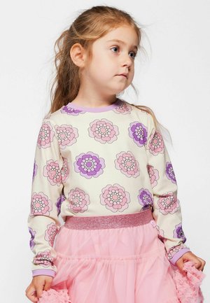 Cămașă crem cu mâneci lungi, decorată cu modele florale mari în nuanțe de mov și roz, cu guler și manșete din reiat mov deschis, asortată cu o fustă roz din tulle.