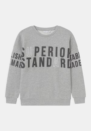 Grå crewneck-sweatshirt med sort og hvid fed tekst, der lyder "SUPERIOR STANDARD" på tværs af brystet og delvist tekst på ærmerne.