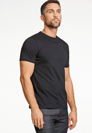 Schwarzes Kurzarm-T-Shirt aus einem glatten Baumwollgemisch, mit Rundhalsausschnitt und taillierter Passform, kombiniert mit dunkelblauen Jeans.