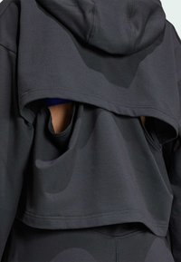 Zwarte sportieve cropped hoodie met een uitsnijdontwerp, voorzien van een zachte, gladde textuur en een capuchon. Duidelijke stofnaden en lagen.