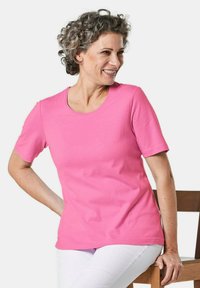 Roze T-shirt met korte mouwen van katoen, voorzien van een ronde halslijn en een relaxte pasvorm. Witte broek maakt de outfit compleet.