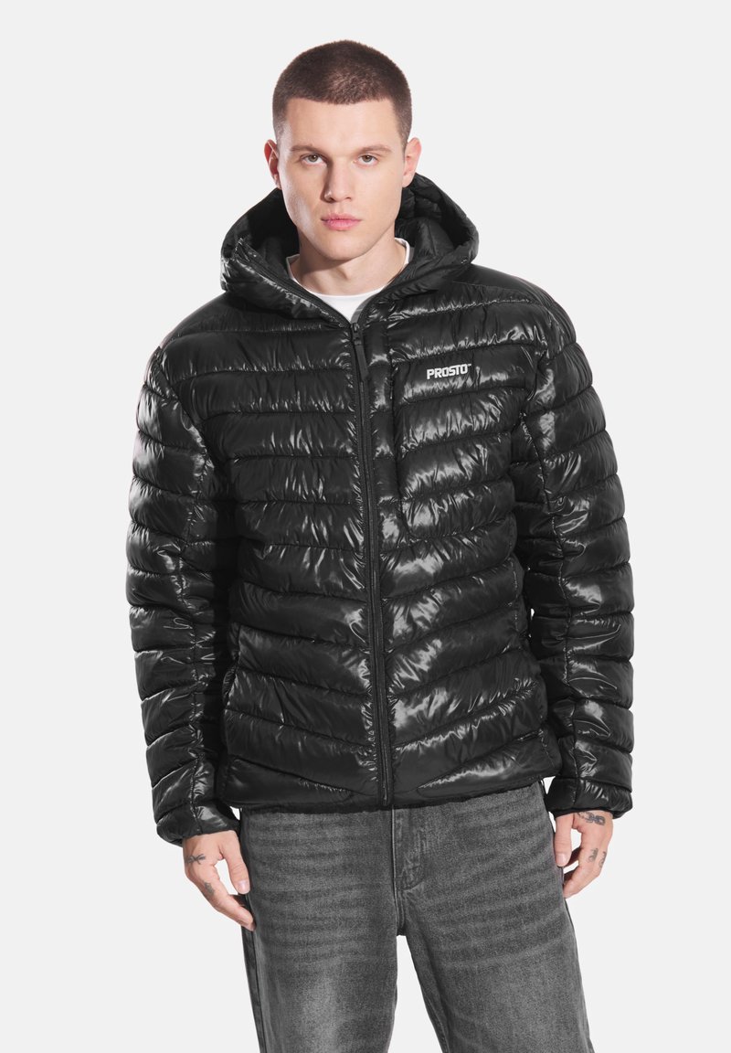 Czarna kurtka puchowa o błyszczącej, pikowanej fakturze, z zamkiem błyskawicznym i kapturem. Na piersi małe logo. Casualowy krój.
