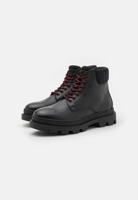 Schwarze Lederstiefel mit runder Zehenpartie und strukturiertem Finish. Sie verfügen über dunkelrote Schnürsenkel, eine robuste Sohle und einen markierten Absatz.