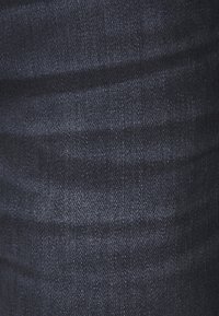 Tumma denimpohja, jossa hienovarainen rakenne, kudottu pinta ja kevyt kiilto. Väriltään syvä indigonsininen, jossa himmeät vaakasuorat viivat.