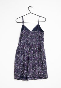 Vestido azul marino con cuerpo fruncido y tirantes ajustables, que presenta un colorido patrón floral en rosa, amarillo y blanco sobre un fondo oscuro.