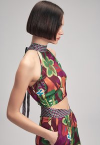 Färgglad halterneck-topp med blommönster i röd, grön och blå. Har en texturerad, mönstrad krage och en croppad design, kompletterad med matchande byxor.