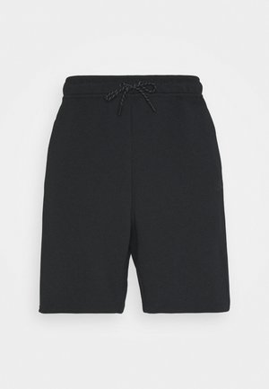Sorte knælange shorts med elastisk talje og sort snor bundet foran på en ensfarvet baggrund.
