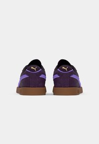 Puma tenisice s gornjim dijelom od ljubičastog sueda, crnim akcentima i smešnim gumiranim potplatom. Imaju teksturiranu površinu i detalj s logotipom na peti.