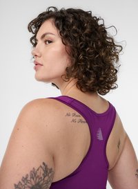 Lila sportliches Tanktop mit Racerback-Design, glattem Material und einem dezenten grafischen Akzent auf dem oberen Rücken. Enthält ein Tattoo-Schriftzug-Detail.