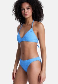 Σετ μπικίνι σε ανοιχτό μπλε, με τριγωνικό τοπ με υφή σπειρώματος και ταιριαστά εσώρουχα. Το υλικό φαίνεται λείο με ρυθμιζόμενους δεσμούς.