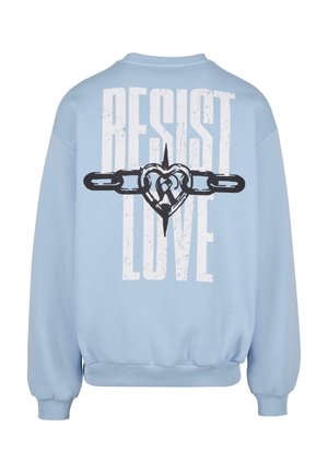 Lyseblå sweatshirt med løs passform, som har stor hvit tekst "RESIST LOVE" og et grafisk bilde av et hjerte med lenker. Myk tekstur, ribbede mansjetter.