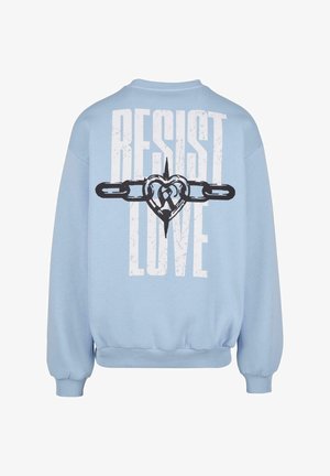 Sudadera azul clara de corte holgado, con un gran texto blanco "RESIST LOVE" y un gráfico de un corazón con cadenas. Textura suave, puños acanalados.
