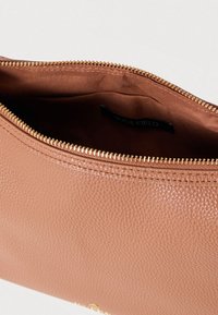 Geantă plic maro din piele texturată, cu închidere cu fermoar auriu. Interiorul are o căptușeală netedă, din material solid, cu etichetă de brand.