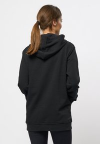 Zwarte hoodie met een ontspannen pasvorm, zachte stof, kangoeroezak en geribde manchetten. Heeft een standaardcapuchon en geen zichtbare grafische afbeeldingen.