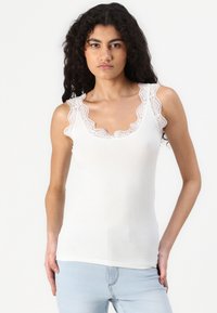 White ribbed tank top with scalloped lace trim at the neckline and shoulders, featuring a fitted design and smooth texture.