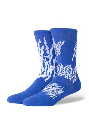Blue socks made from knit fabric, featuring a white abstract pattern. Includes ribbed cuff and contrasting green accent at the toe.
