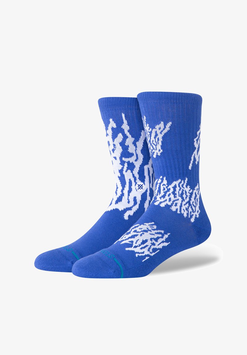 Blue socks made from knit fabric, featuring a white abstract pattern. Includes ribbed cuff and contrasting green accent at the toe.