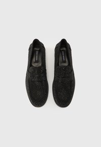 Chaussures slip-on noires avec dessus texturé orné de perles, bout rond et semelle intérieure rembourrée. Semelle extérieure en caoutchouc pour adhérence et durabilité.