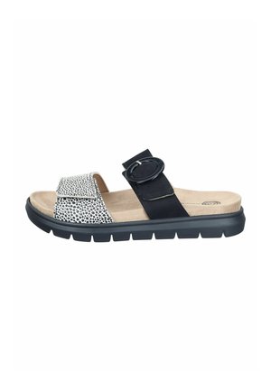 Open-toe sandal with black and white spotted front strap, black adjustable middle strap with large buckle, beige cushioned footbed, and black sole.