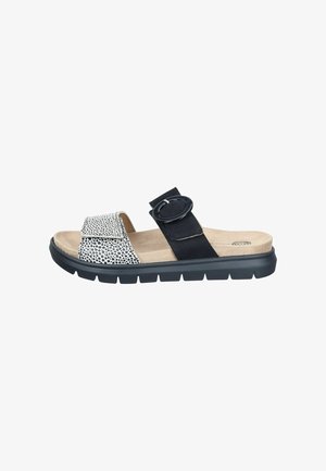 Open-toe sandal with black and white spotted front strap, black adjustable middle strap with large buckle, beige cushioned footbed, and black sole.