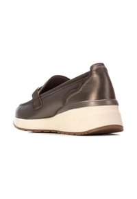 Zapatos de cuero marrón de tipo mocasín con una forma redondeada, un collar acolchado y una suela gruesa de color claro. Presentan detalles de costura sutiles.