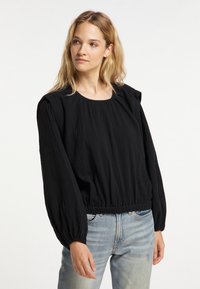 Zwarte blouse met lange mouwen en een ronde halslijn, voorzien van geplooide schouderdetails en een elastische tailleband. Gemaakt van gestructureerde stof en heeft een losse pasvorm.