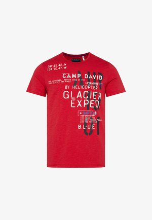 T-shirt rossa in cotone con colletto girocollo, maniche corte e grafica in bianco e nero, con dettagli blu. Il testo include coordinate e frasi.