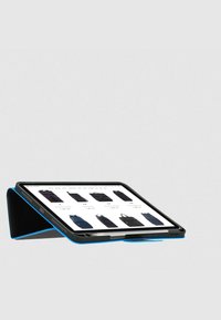 Funda negra para tablet con detalles azules, vista en ángulo, mostrando una pantalla con varios diseños de bolsas en un diseño de cuadrícula.