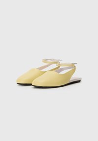 Geltoni odiniai bateliai su slingback stiliumi, lygia apdaila, smailiu nosiu ir plona kulkšnies juosta. Juodas padas ir minimalizmas dizainas.