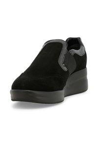 Scarpe slip-on nere in suede con dettagli elastici e una suola piatta spessa. La tomaia presenta una texture liscia e un design minimalista.
