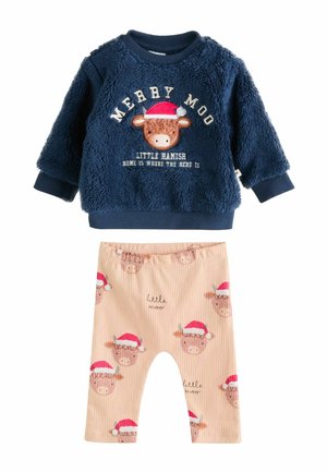 Marineblaue, flauschige Sweatshirt mit Text und Kuhdesign, kombiniert mit beigen, gestreiften Hosen, die Kuhgrafiken und den Schriftzug "little moo" zeigen.