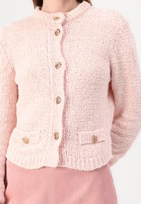 Ljusrosa stickad kofta med rundad krage, fem prydliga guldknotter och två framfickor med liknande knappdetaljer.