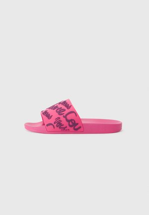 Tongs en caoutchouc rose avec une large lanière présentant un design graphique manuscrit noir. Semelle plate au fini texturé.
