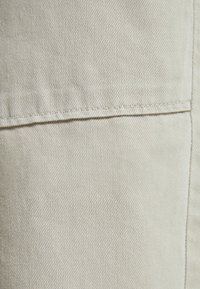 Beige kangas na diagonal twill weave na na stitching ya sambamba katikati.