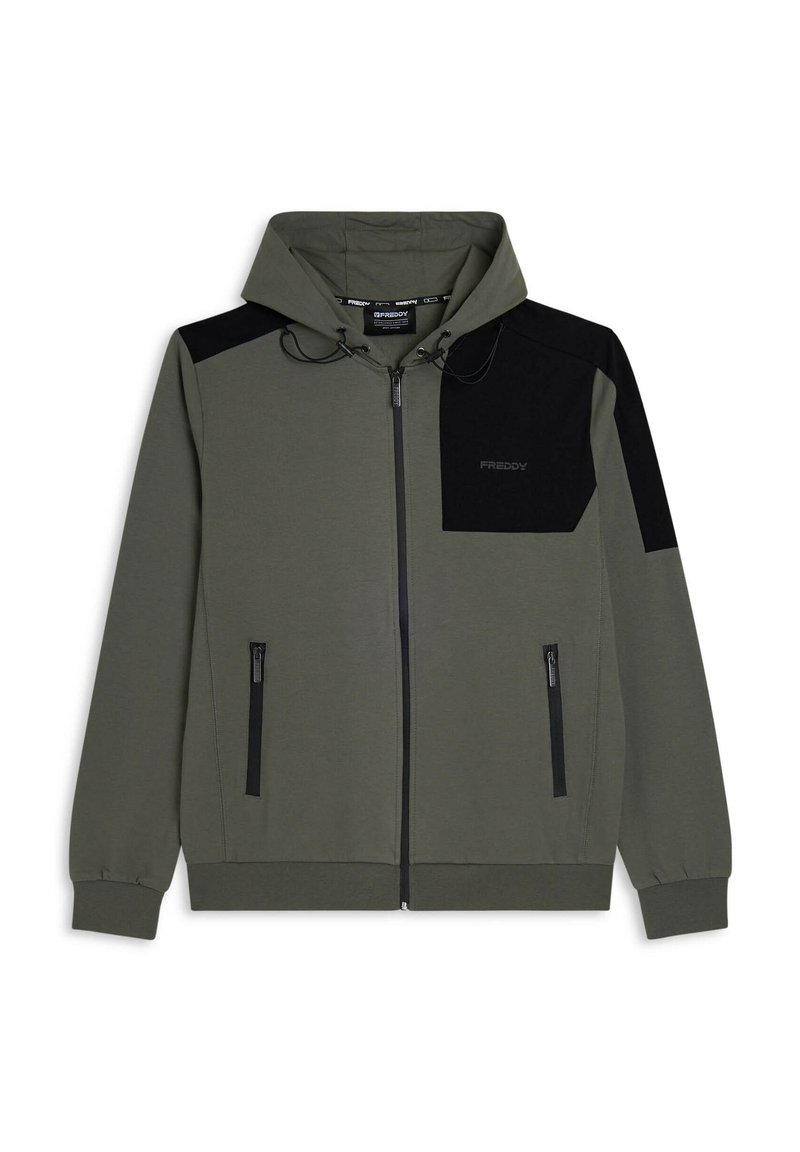Sudadera con capucha de color verde oliva con cierre de cremallera, con un panel negro en un hombro, que incluye bolsillos frontales con cremallera y cordón en la capucha. Fabricada con un material suave.