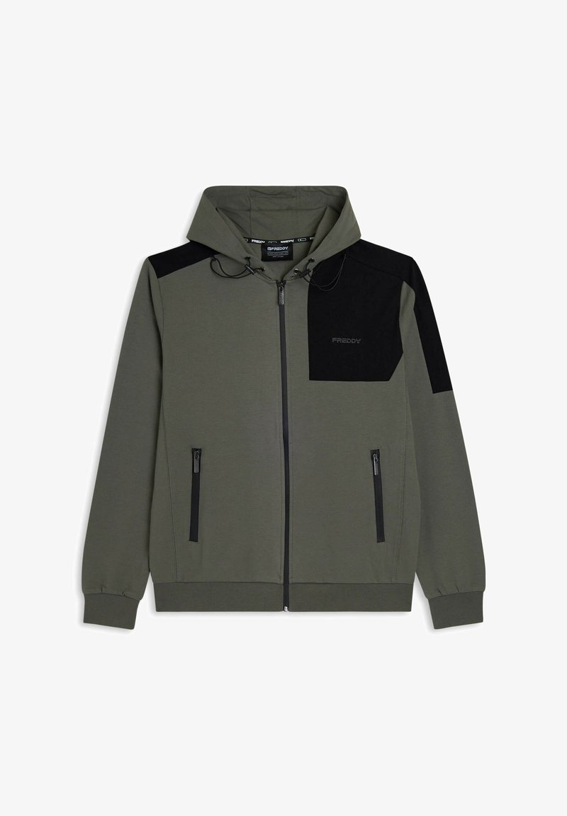 Sudadera con capucha de color verde oliva con cierre de cremallera, con un panel negro en un hombro, que incluye bolsillos frontales con cremallera y cordón en la capucha. Fabricada con un material suave.