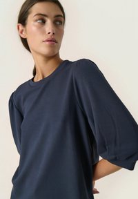 Navy blauwe pull-over met een ronde halslijn en korte puff-mouwen, gemaakt van zachte stof, met een gladde textuur en een minimalistisch ontwerp.