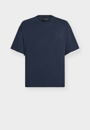 T-shirt de algodão azul marinho com mangas curtas. Apresenta decote redondo e realces contrastantes em branco nas bordas das mangas. Pequeno logótipo no peito.